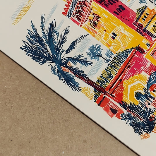 Close-up angled detail of the Kutubiyya Mosque print showing the printed surface and colourful sketch lines up close. Palm leaves, building edges and parts of the Marrakech street scene are visible in red, yellow and blue tones, giving a clearer view of the artwork finish and composition. A useful detail image for Morocco wall art, Marrakech art print and travel poster shoppers wanting a closer product view.