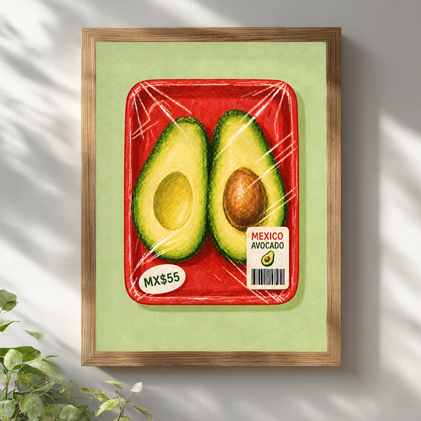 Mexican avocado kitchen print in a natural wooden frame on a white wall, lit by soft sunlight with leafy shadows across the artwork and surrounding wall.