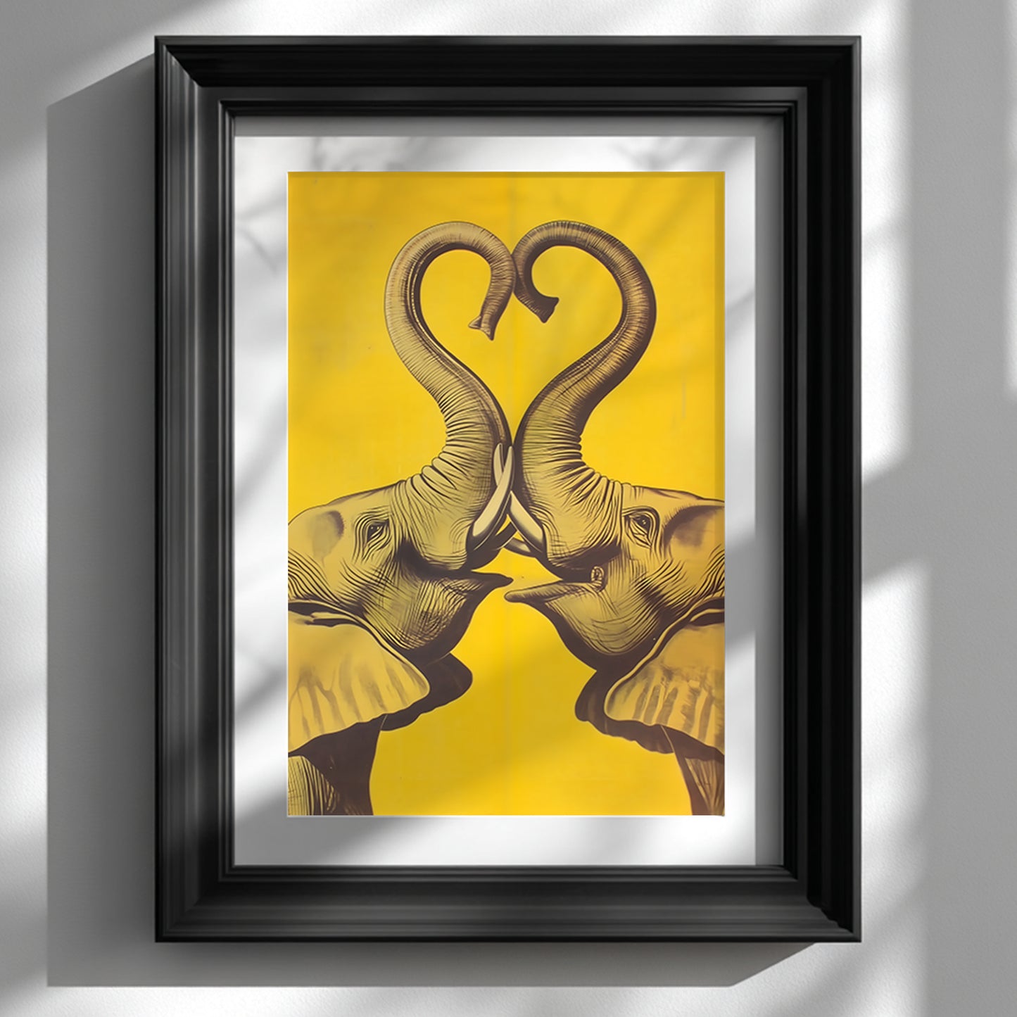 Black framed Elephant Heart elephant poster displayed on a white wall with soft window light and shadows. The artwork shows two mirrored elephants facing each other, their trunks raised into a heart shape in dark linework on a bold yellow background. Styled mockup for elephant wall art, elephant print, yellow elephant poster, framed elephant print, and modern elephant wall decor.