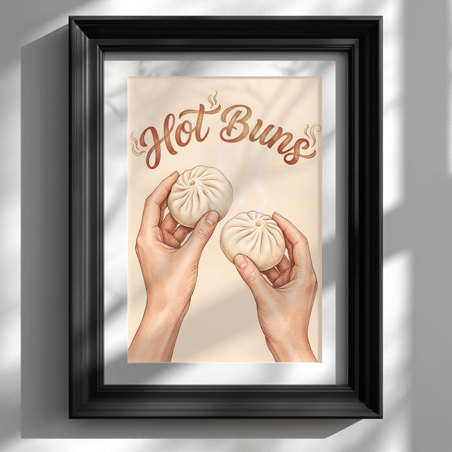 Framed Hot Buns asian food wall art shown in a black frame with a white mount against a clean white wall. The print features two hands holding steamed bao buns under curved brown lettering that reads “Hot Buns” on a soft beige background. Styled as funny kitchen wall art with a simple modern look, ideal for kitchen decor, dining room food art, and contemporary foodie interiors.