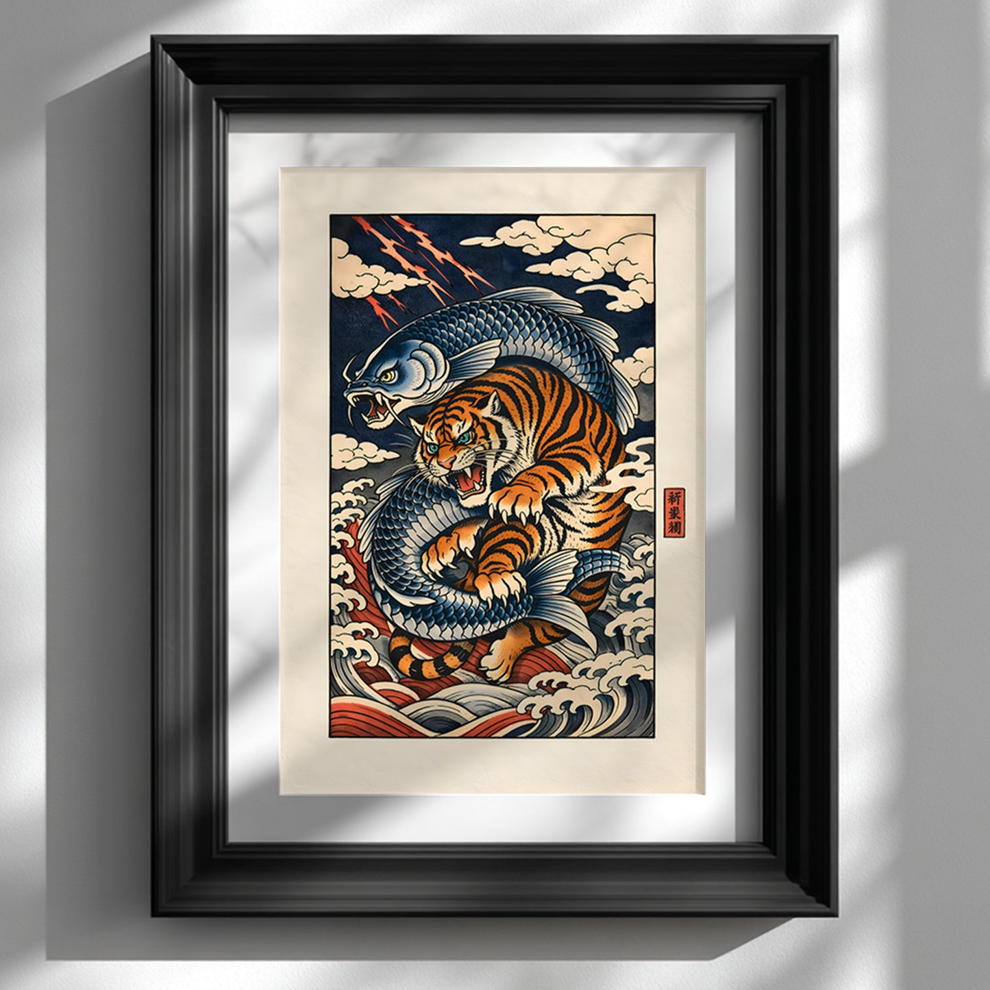 Black framed Japanese tiger and ocean wave wall art print displayed on a clean white wall. The artwork features a dynamic orange tiger curled among stylised blue waves in traditional ukiyo-e inspired design, with bold linework and contrasting navy, cream and rust tones. Contemporary interior styling highlights this framed Asian tiger artwork as a striking statement piece.