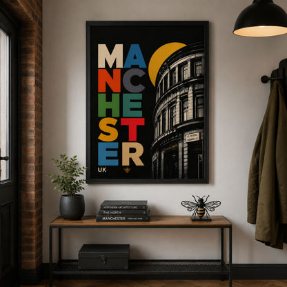 Manchester Central Library poster displayed in a black frame above a dark wood console table, with warm wall lighting, a small plant and modern living room styling.