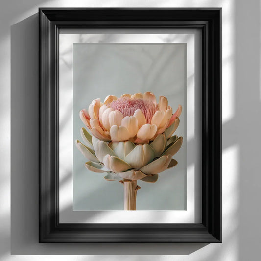 A framed pastel artichoke wall art print displayed on a clean white wall, styled in a modern black frame. Soft natural lighting and neutral décor highlight the artwork’s gentle pastel tones and botanical detail.