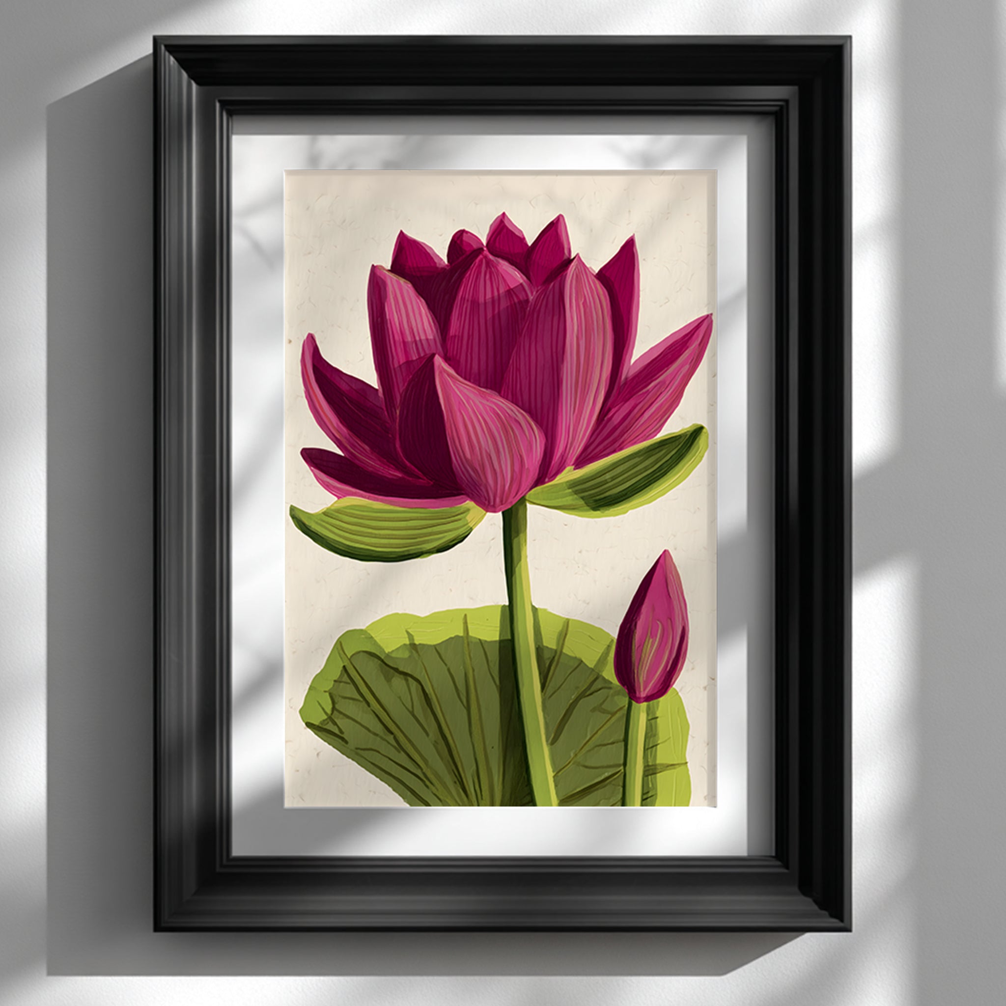 Framed pink lotus flower wall art in a black frame mounted on a white wall. The poster shows a large pink lotus bloom with layered petals, green stem, broad base leaf and smaller bud on a soft beige background. East Asian inspired botanical print styled as zen meditation decor for modern living rooms, bedrooms and minimalist interiors.