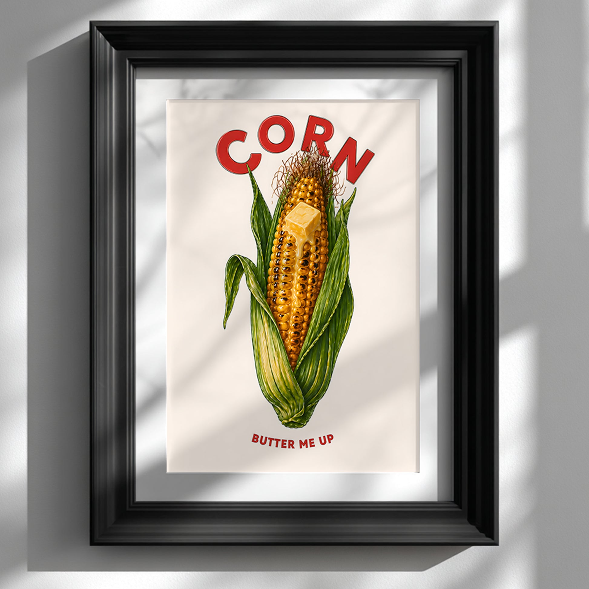 Black framed corn butter poster shown vertically on a clean white wall. The artwork features a bright corn on the cob with green husks, melting butter, red CORN lettering and BUTTER ME UP text below. A bold funny food poster for kitchens, cafés, dining rooms and playful gallery walls.