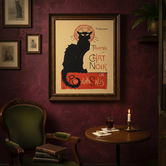 Framed Tournée du Chat Noir poster styled in a moody, vintage-inspired living room with deep red walls, classic green chair and candlelit table. The French Art Nouveau black cat print stands out as a focal point, reflecting bohemian Paris nightlife and historic cabaret culture. A dramatic example of vintage French theatre wall art in a rich interior setting.
