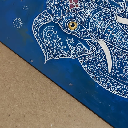 Close-up detail image of the Blue Elegant Elephant Print showing the artwork surface from an angled view. The visible section highlights the elephant’s gold eye, white tusk, white decorative linework and rich blue background, along with the edge of the print. A useful detail shot for blue elephant art print, Indian elephant artwork, ornate animal wall art and print quality presentation.