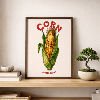 Corn butter poster displayed on a shelf beside a small bonsai-style plant in a calm modern room. The print shows a golden corn cob, green husks, melting butter and bold red lettering. A playful corn kitchen poster for shelves, dining spaces, cafés and simple food wall art styling.