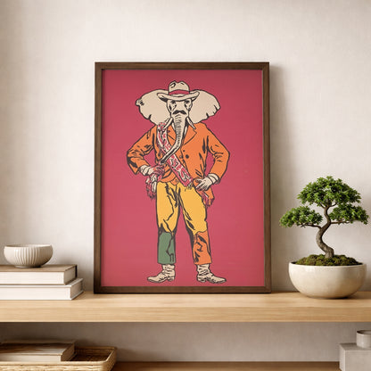 Elephant Cowboy poster leaning on a shelf in a clean modern room with stacked books and a bonsai plant. The print shows a playful elephant cowboy in a hat, orange jacket, yellow trousers and boots against a bold red background. Ideal as western wall art, cowboy poster or funny animal decor for minimalist homes, eclectic spaces, offices and modern gallery walls.