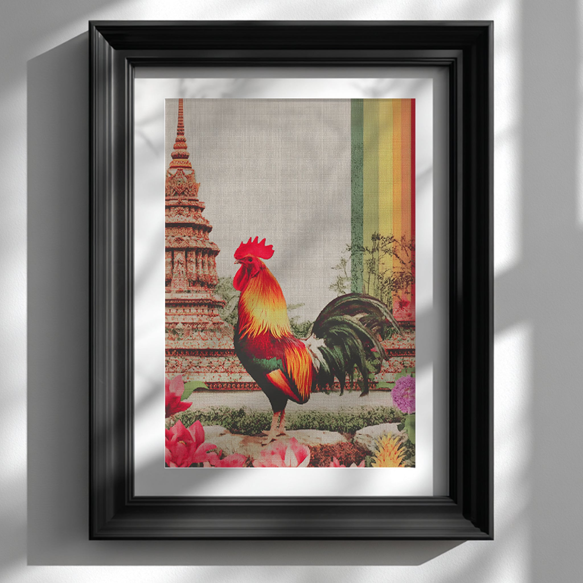 Framed Thai rooster wall art mounted on a clean white wall in a sleek black modern frame. The artwork shows a vibrant crimson and gold rooster standing before a pagoda inspired by Wat Arun, with visible canvas-style texture and a bold vertical multicolour rainbow stripe. Soft natural light casts shadows, presenting this as gallery-style cultural decor suitable for contemporary feature walls, hallways or dining spaces.
