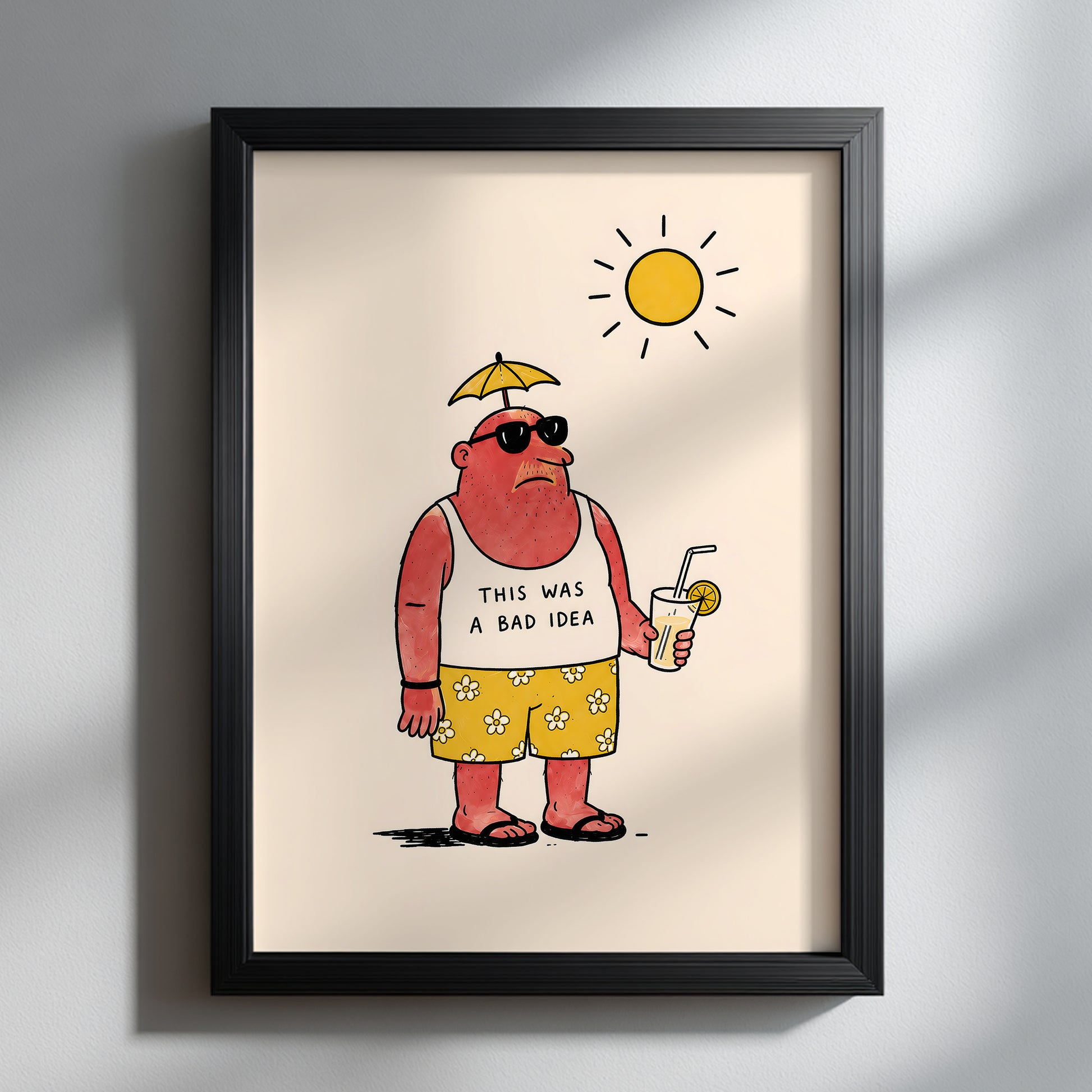 Funny travel poster displayed in a black frame on a clean white wall. The artwork shows a sunburnt man in sunglasses, flower shorts and flip flops holding a cold drink, with “THIS WAS A BAD IDEA” on his vest. A simple sarcastic holiday print for modern travel decor and funny wall art.
