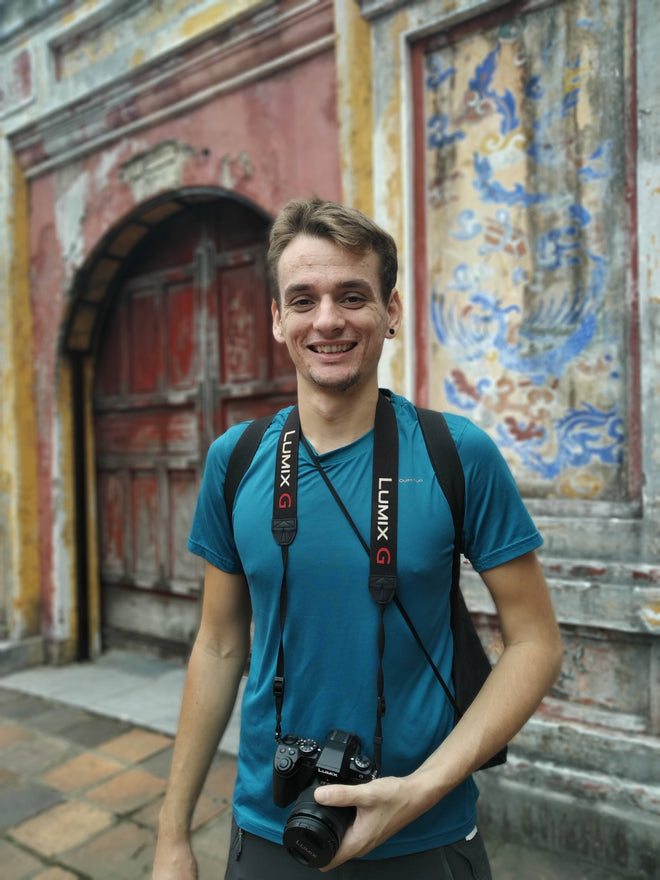 Photo of Jack - Founder of CITTRA Collective - in Vietnam. He is holding a camera and wearing a blue tshirt with a big smile.
