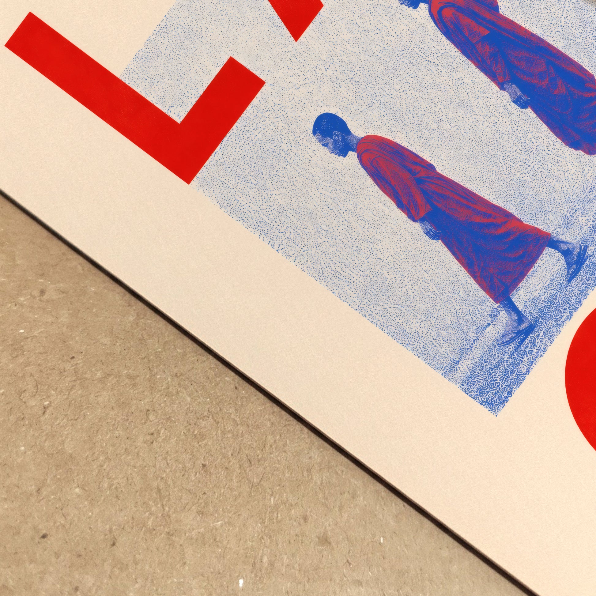 Close-up of the Laos monk art print lying on a textured surface, showing the cream paper, blue halftone pattern, red lettering and detailed figures of two Buddhist monks in red robes.