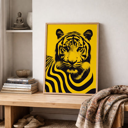 Framed Malaysian tiger wall art print displayed on a wooden shelf with folded textiles and neutral home decor. The poster features a bold black tiger portrait with flowing striped wave patterns on a vibrant yellow background, forming a striking contemporary wildlife artwork inspired by Malaysia’s national animal and modern cultural design.