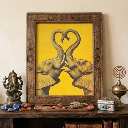 Elephant Heart framed elephant wall art shown in a warm travel-inspired interior with an ornate wooden frame, decorative objects, and a rich cultural styling setup. The yellow elephant print features two mirrored elephants with trunks forming a heart. Lifestyle image for elephant poster, framed elephant print, asian elephant wall art, thai elephant art, and cultural wall decor.