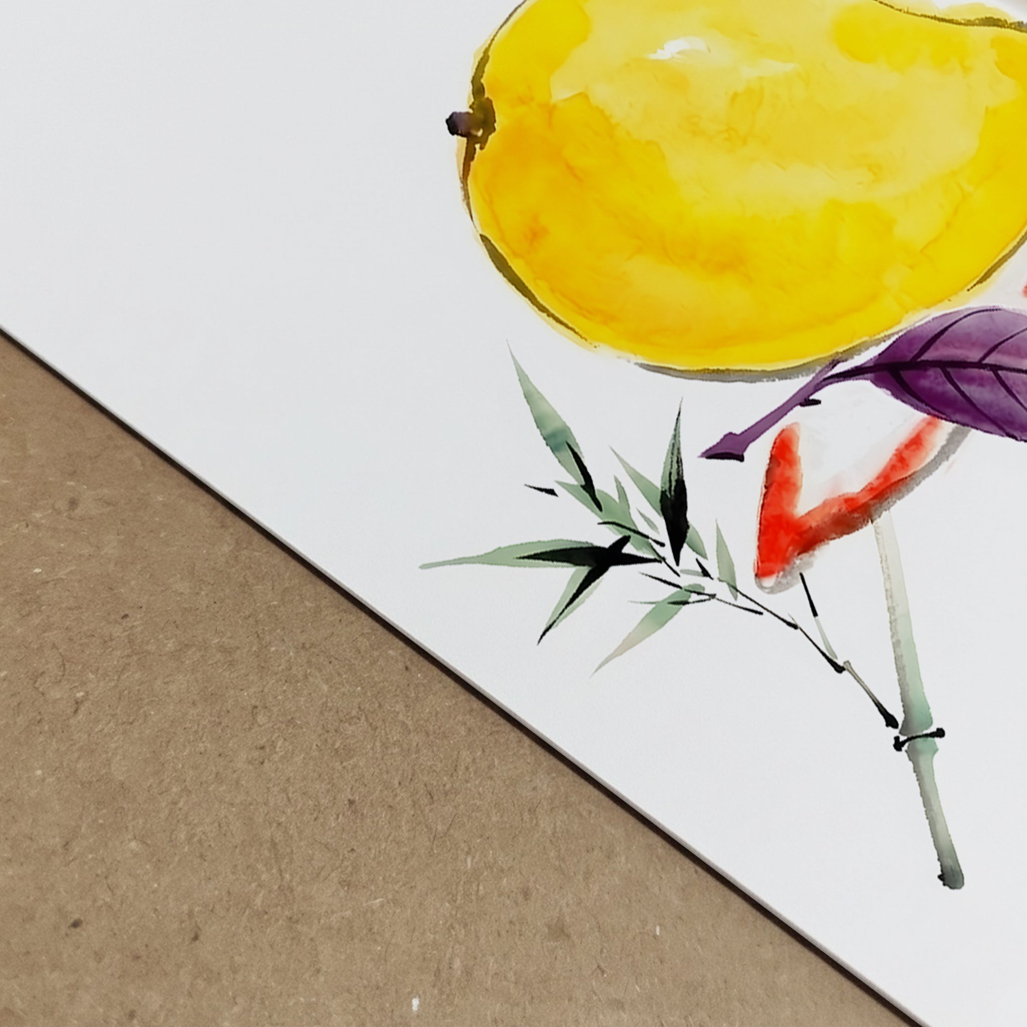 Close-up detail image of the mango print showing the lower edge of the paper, the white background and part of the painted fruit and leaves against a textured neutral surface. The cropped view highlights the clean print finish, paper edge and watercolour detail in the yellow mango and foliage. Useful for showing the quality and surface look of the mango art print, botanical fruit print or tropical kitchen wall art.
