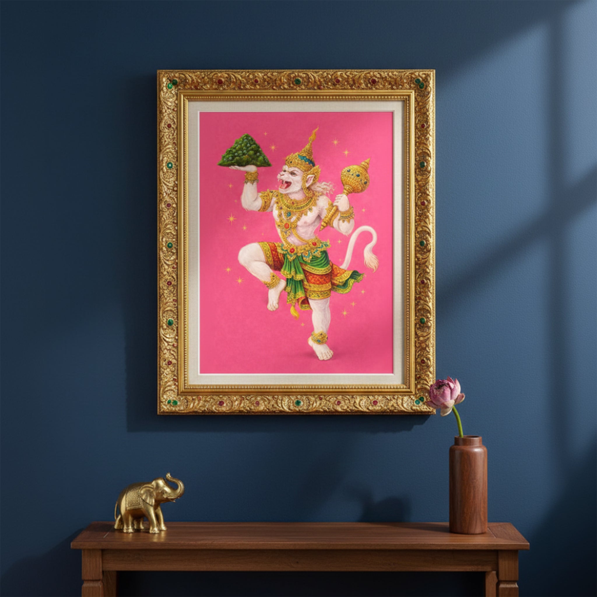 Thai Hanuman Ramakien art print presented in an ornate gold frame styled on a dark interior wall. The vivid pink background contrasts with the classical frame, showcasing the Hindu monkey god in traditional Thai costume. A striking spiritual mythology wall decor piece blending heritage Ramakien imagery with refined, gallery-style interior design.