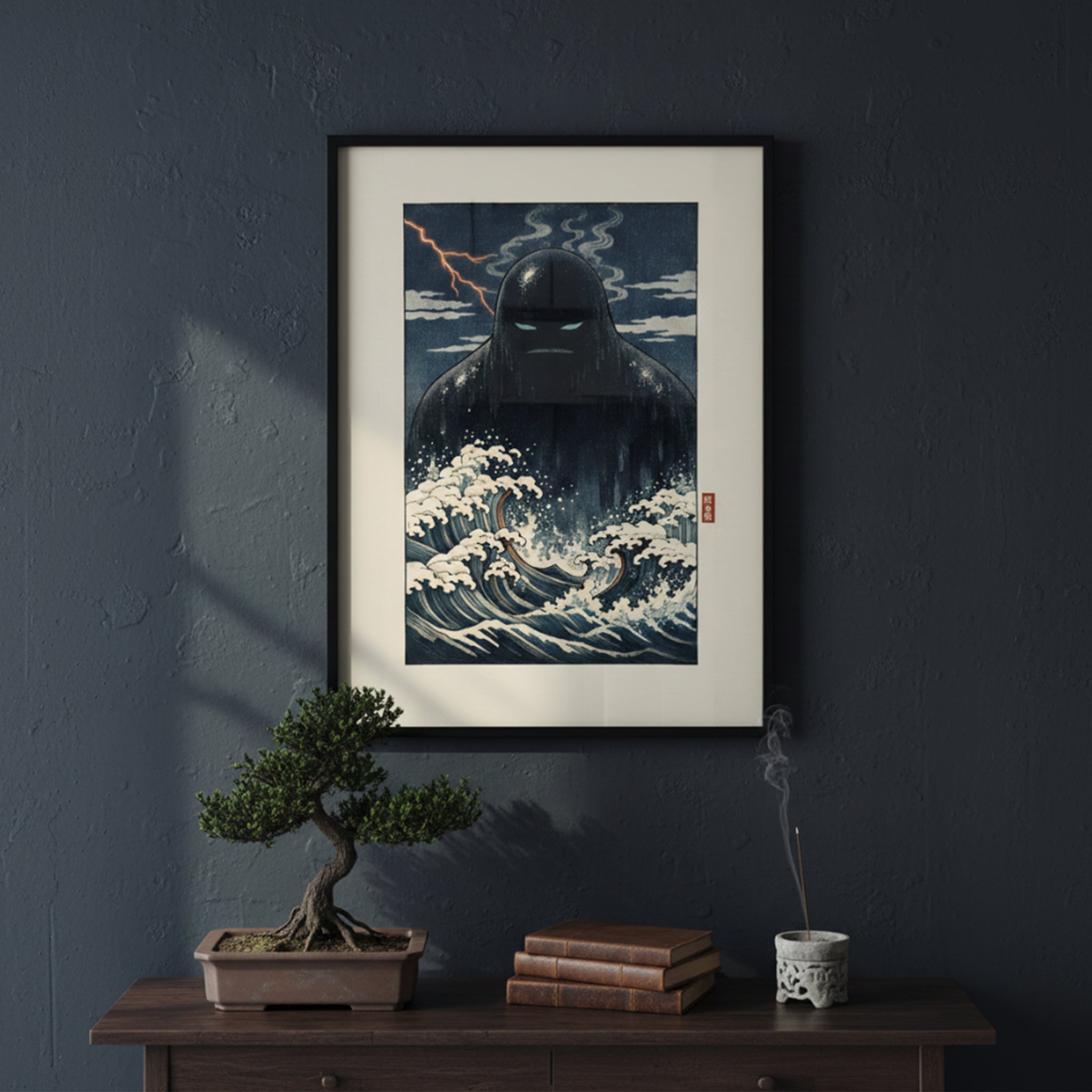 Framed Japanese folklore print of the Umibōzu sea monk displayed on a dark painted wall above a wooden console table. The artwork shows a shadowy sea spirit rising from churning waves in deep blue and cream tones. Styled with a small potted plant and minimal decor, this yōkai wall art creates a dramatic cultural focal point.