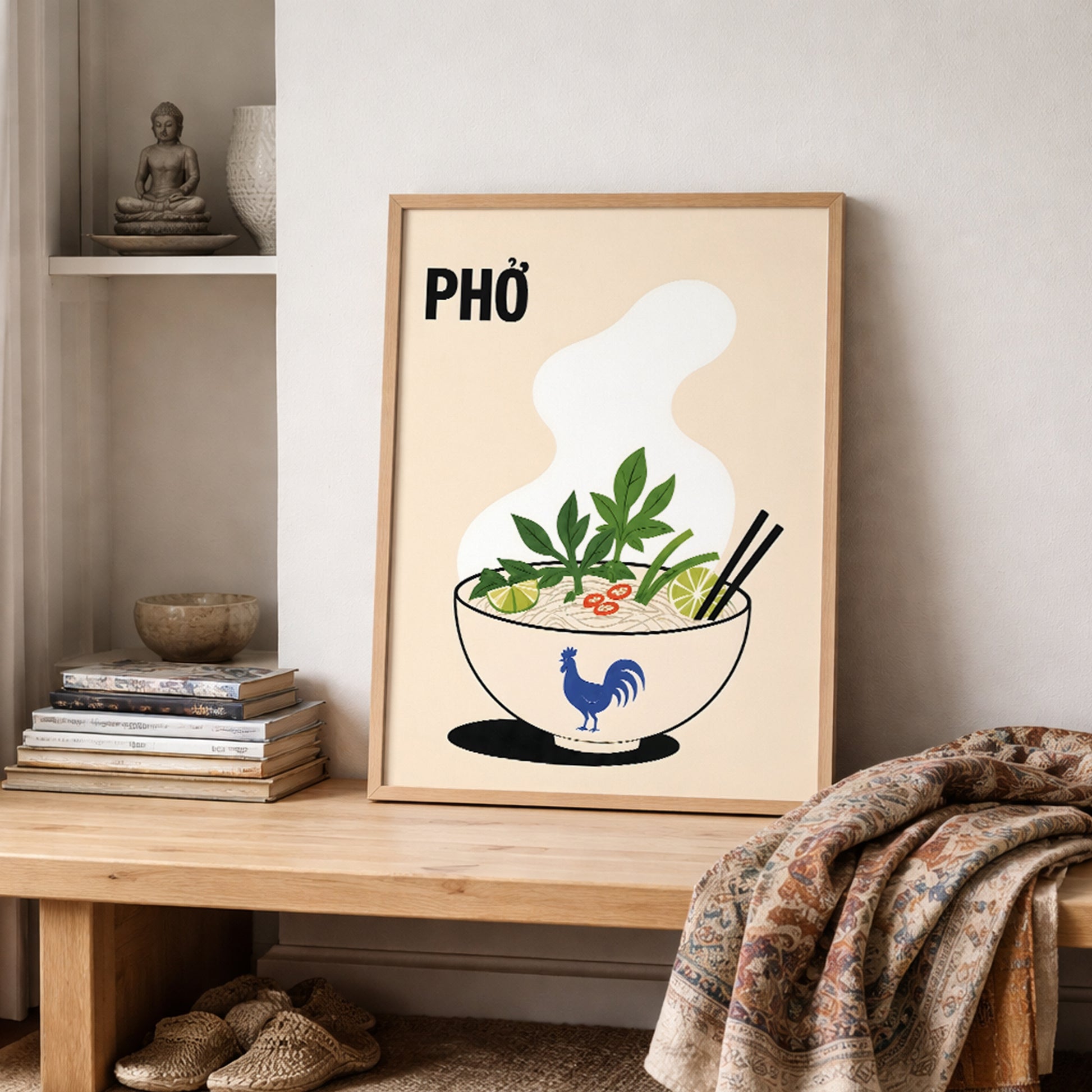 Vietnamese pho poster leaning on a shelf in a warm neutral interior beside stacked books, ceramics and a patterned textile. The food illustration features a steaming noodle bowl with herbs, lime, chilli and chopsticks.