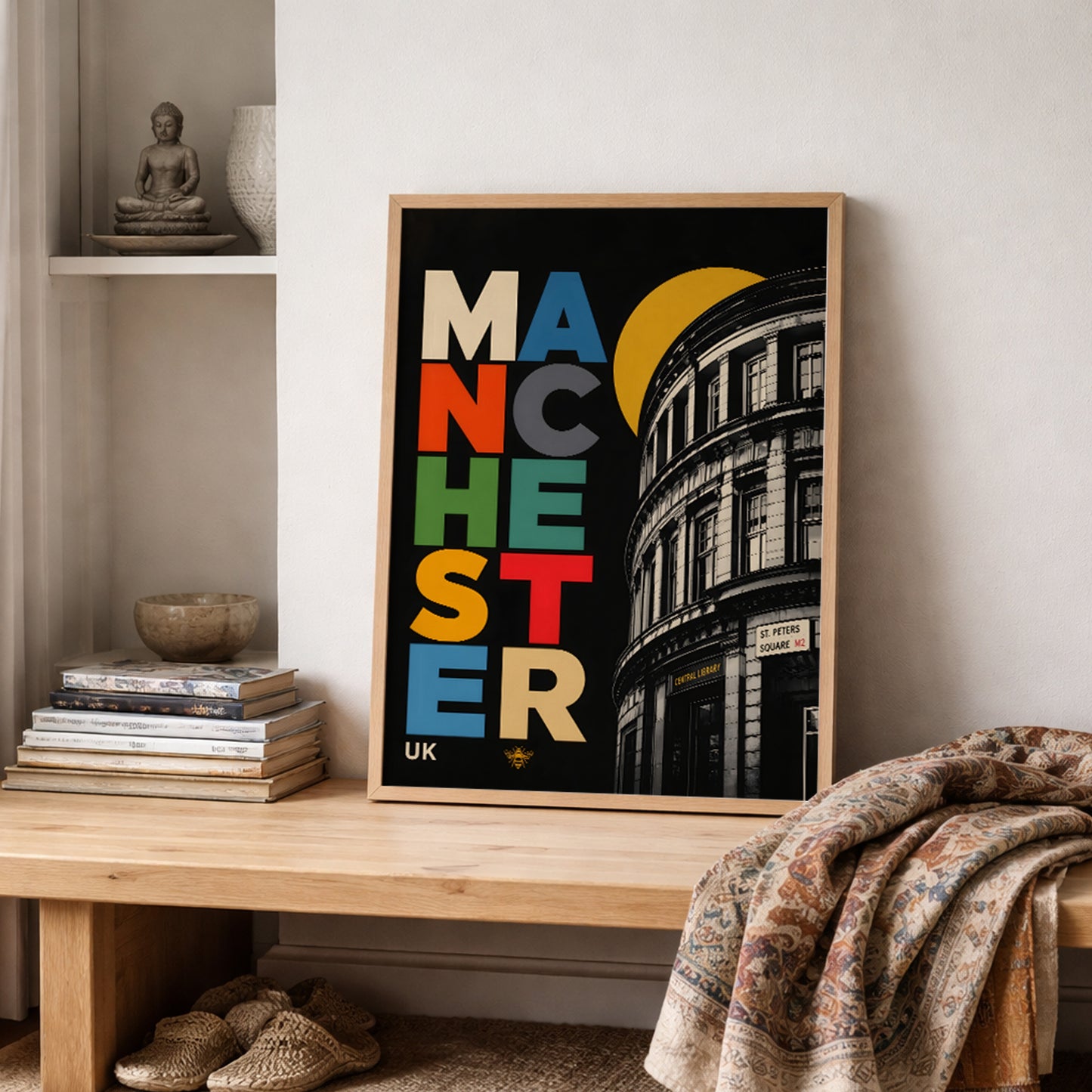 Manchester Central Library print in a wooden frame on a shelf beside neutral books and folded textiles, styled in a warm, lived-in interior with soft natural tones.