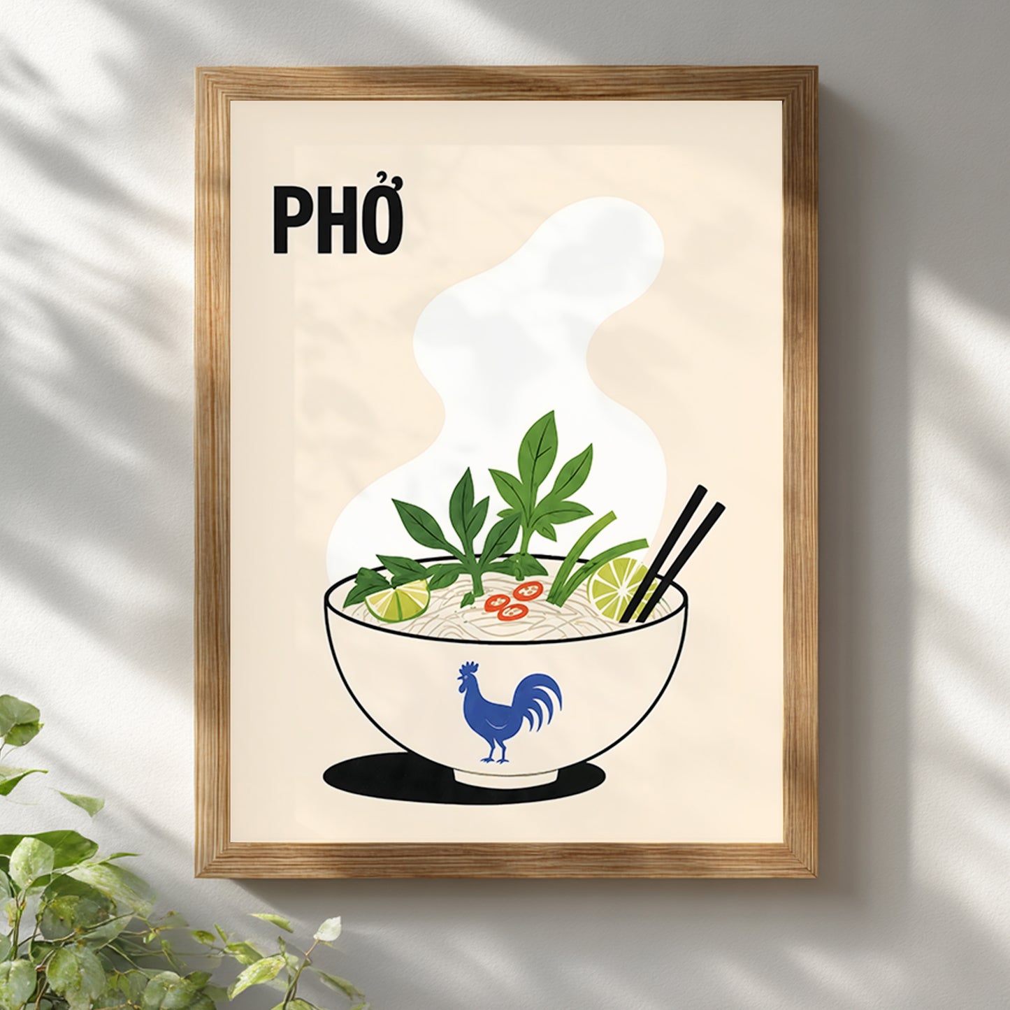 Vietnamese pho poster displayed in a light wooden frame on a white wall with soft leaf shadows. The cream kitchen print features PHỞ text, rising steam and a noodle soup bowl with herbs, lime, chilli and chopsticks.