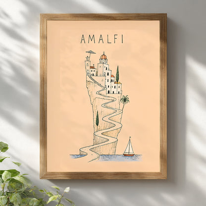Wooden-framed Amalfi Coast travel print displayed on a sunlit white wall, featuring a peach background, winding coastal road and illustrated Italian cliffside village.